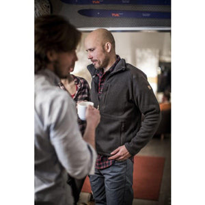 Man wearing a dark grey Fjallraven fleece jacket over a red plaid shirt