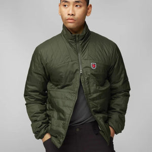 Man wearing a dark green FjallRaven quilted jacket with a high collar and logo patch