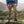 Person wearing FjallRaven beige hiking trousers and brown boots standing on a mossy rock in a mountainous landscape