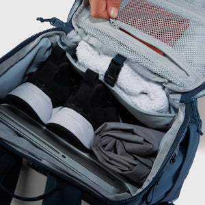 Open Under Armour backpack showing internal compartments with shoes towel and laptop