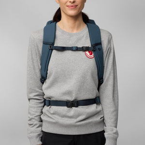 Person wearing a blue Fjallraven backpack with chest and waist straps fastened
