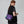 Person wearing a purple Fjallraven crossbody bag over a black fleece vest