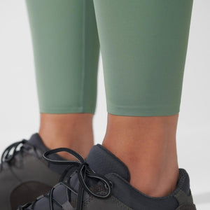 Close up of sage green leggings and black athletic shoes