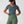Person wearing a blue striped short sleeve v-neck top and olive green high waisted leggings with a black cap