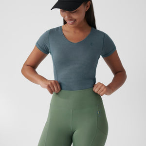 Person wearing a blue striped short sleeve v-neck top and olive green high waisted leggings with a black cap
