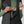 Person pulling a compass from the chest pocket of a black FjallRaven quilted vest