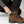Person adjusting the snap button strap on the hem of black FjallRaven trousers over a brown Hanwag hiking boot
