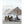 People sitting in camping chairs under a large tarp on a beach with ocean waves in the background