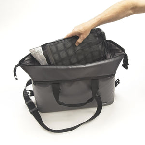 Hand placing a mesh bag containing ice packs into a grey insulated cooler bag