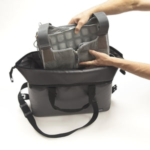 Hands placing a FlexiFreeze ice pack insert into a grey cooler bag