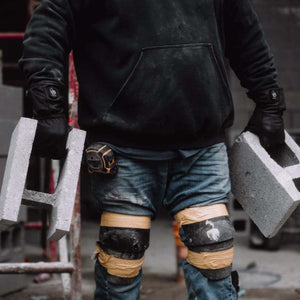 Person wearing FNDN heated gloves carrying concrete blocks