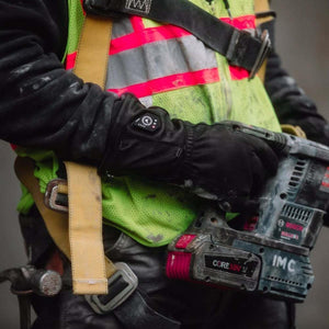 Worker wearing high visibility vest and heated gloves holding a Bosch power tool