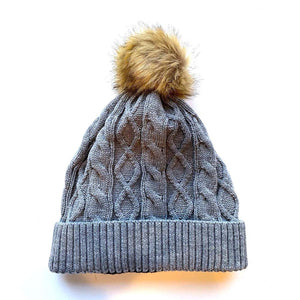 Grey cable knit beanie with a brown faux fur pom pom
