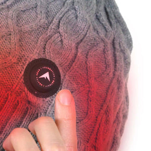 Close up of a grey cable knit beanie with a circular Heated Gear Foundation Detroit logo patch