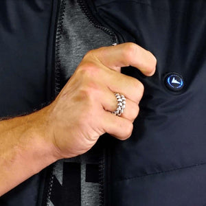 Hand pressing the FNDN logo power button on a black heated jacket