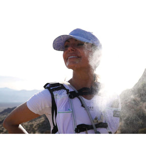 Runner wearing a Gore running vest and cap with water mist in the air