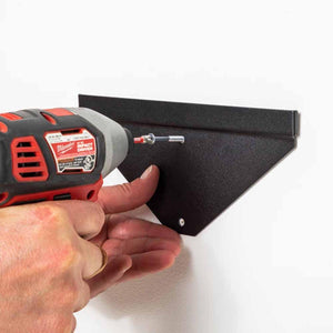 Hand using a power drill to mount a black GearDryer wall bracket