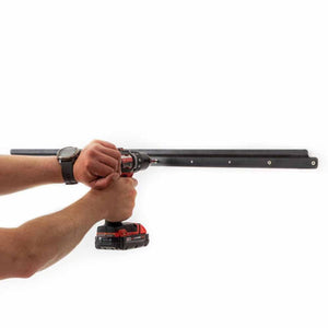 Person using a power drill to mount a GearDryer black metal wall bracket