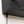 Black power cord plugged into the underside of a black electronic device with a perforated metal casing