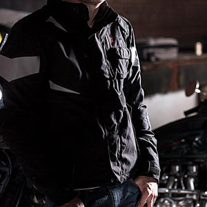 Person wearing a black textile motorcycle jacket with reflective accents