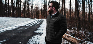 Man wearing a black Gerbing puffer jacket standing on a snowy road