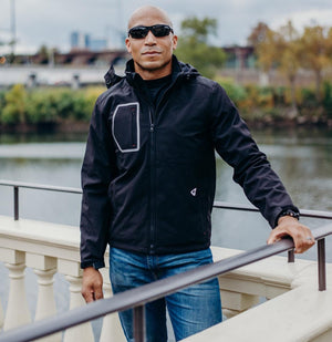 Man wearing a black Gerbing softshell jacket standing by a railing
