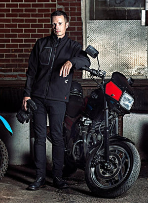 Man wearing black motorcycle jacket and jeans standing next to a black motorcycle