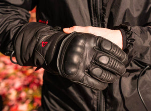 Person wearing black leather motorcycle gloves with knuckle protection