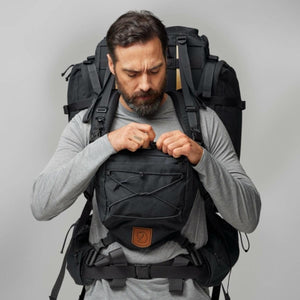 Man wearing a black Fjallraven backpack with a front accessory pouch