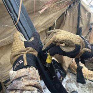 Hands wearing Glacier Glove tan and black tactical gloves loading a shotgun shell