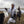 Woman wearing Glacier Glove gear holding two geese in a field with a black dog