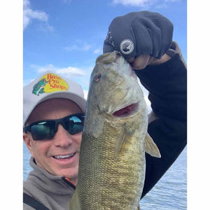 Angler wearing a Bass Pro Shops hat holding a smallmouth bass