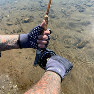 Person wearing Glacier Glove fingerless fishing gloves holding a fly fishing rod over water