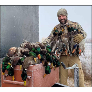 Man wearing Glacier Glove gear holding harvested mallard ducks outdoors