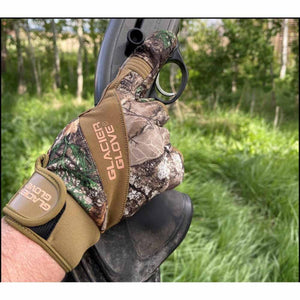 Glacier Glove camouflage shooting glove worn on hand holding a firearm in a grassy outdoor setting