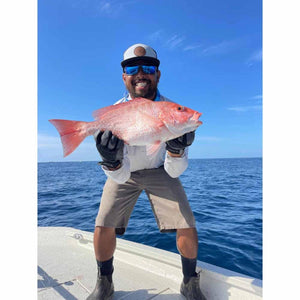 Angler wearing Glacier Glove fishing gloves holding a red snapper on a boat