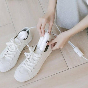 Person inserting white Glovii electric shoe dryer into a white sneaker
