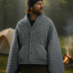 Man wearing a grey quilted Gobi Heat heated poncho at a campsite