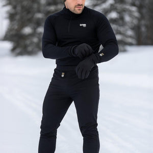 Man wearing Gobi Heat black heated base layer top and pants in a snowy outdoor setting
