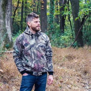 Man wearing a Gobi Heat camouflage hooded jacket in a forest
