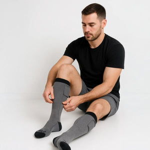 Man wearing Gobi Heat grey heated socks while sitting on the floor