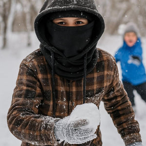 Child wearing a Gobi Heat brown plaid shirt and black face mask holding a snowball outdoors in winter