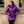 Woman wearing a purple Gobi Heat hooded puffer jacket against a brick wall