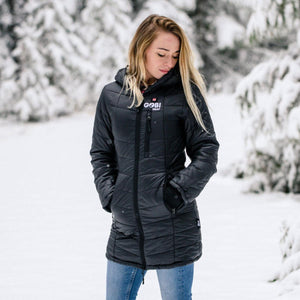 Woman wearing a black Gobi Heat hooded jacket in a snowy forest