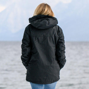 Back view of a person wearing a black hooded jacket by a lake