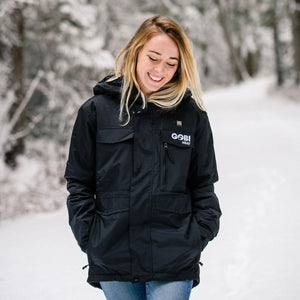 Woman wearing a black Gobi Heat jacket in a snowy forest