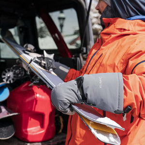 Person wearing Gordini Gore-Tex mittens holding skis near a vehicle