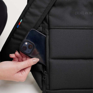 Hand placing a smartphone into the side pocket of a black Got Bag backpack