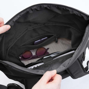 Interior of a black Got Bag backpack showing a laptop sleeve and zippered pocket containing sunglasses and a phone