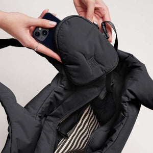 Hands placing a smartphone into a small black Got Bag pouch attached to a larger black tote bag